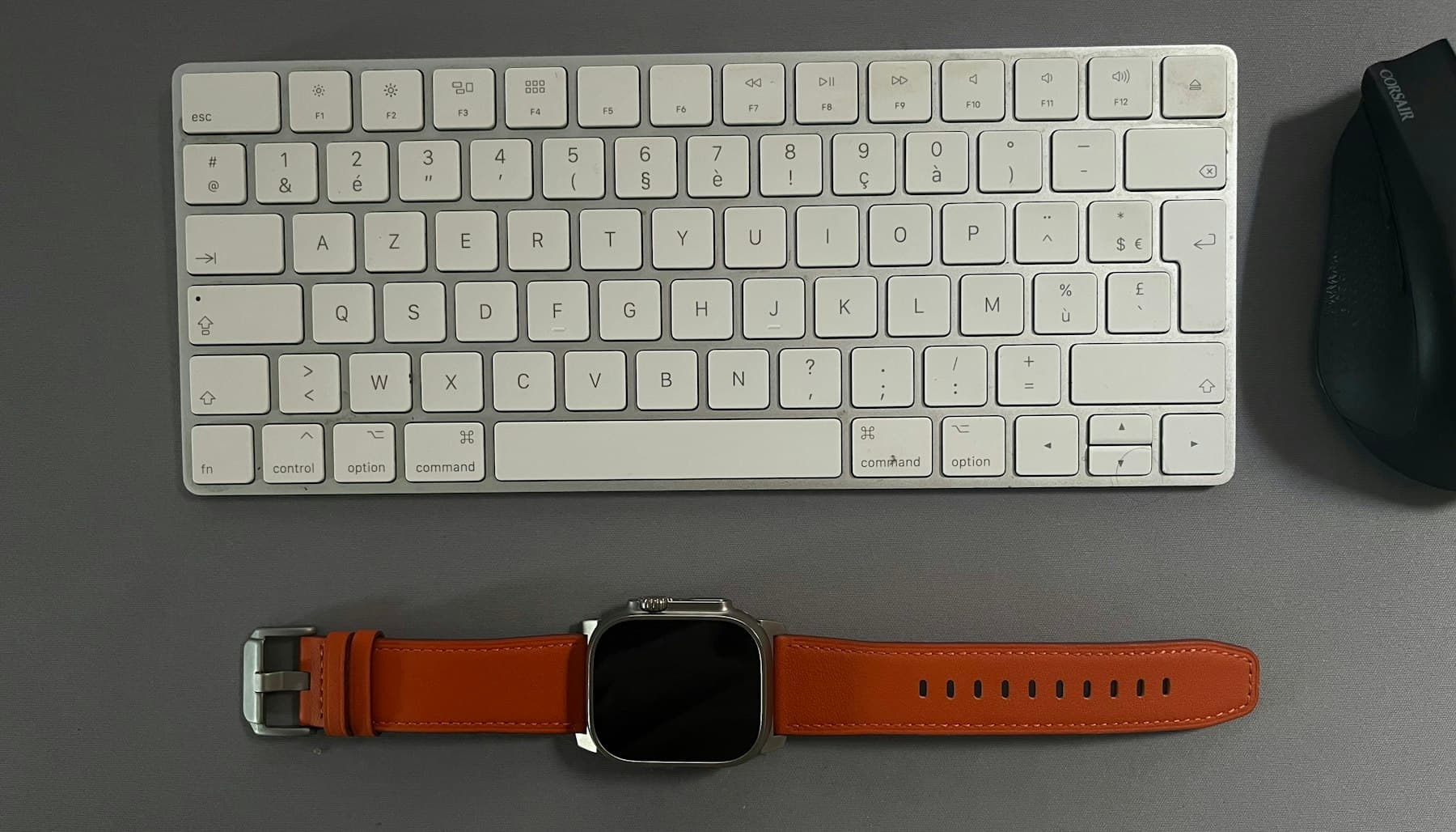A smartwatch next to a white keyboard on a light desk