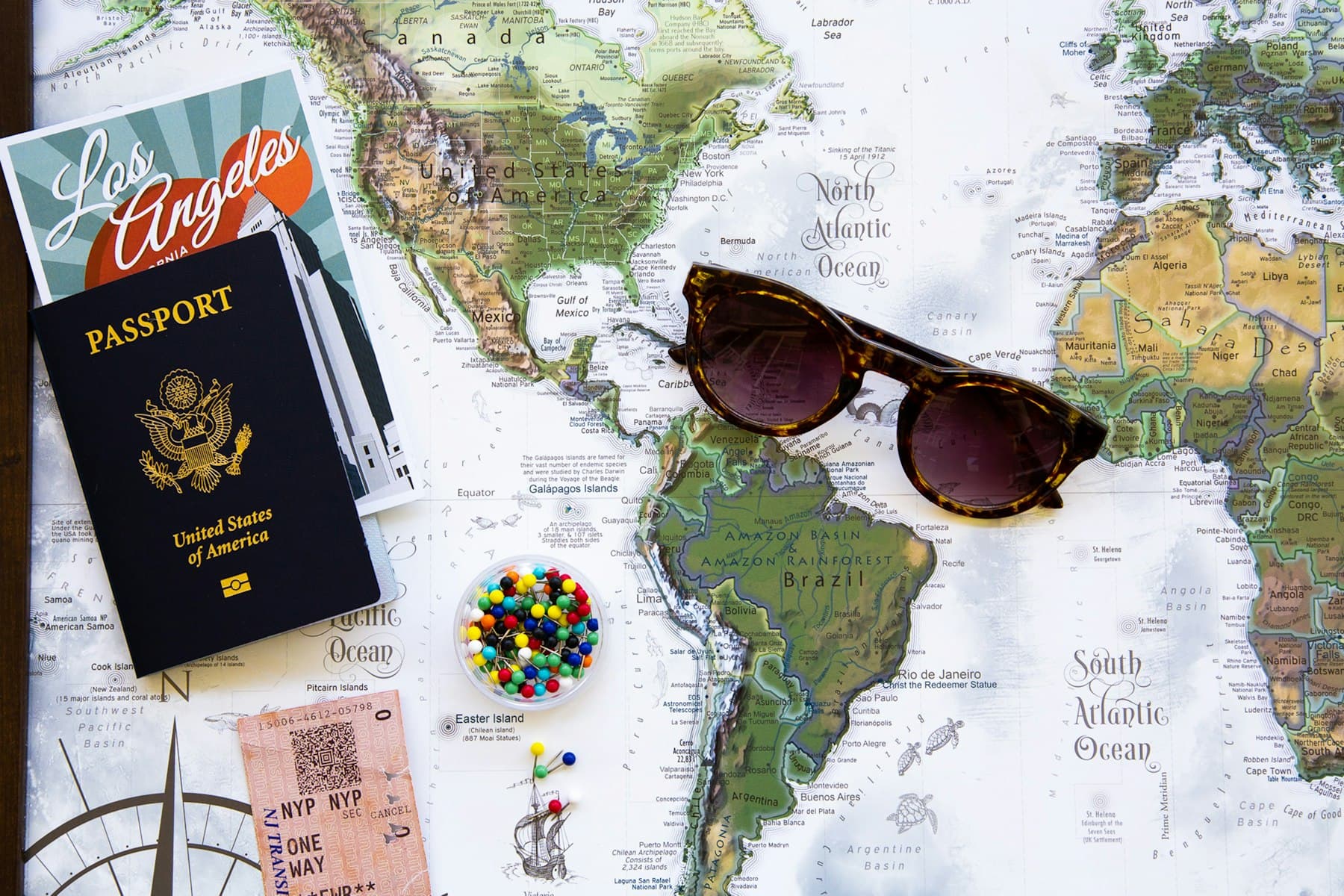 A passport and sunglasses lying on a world map